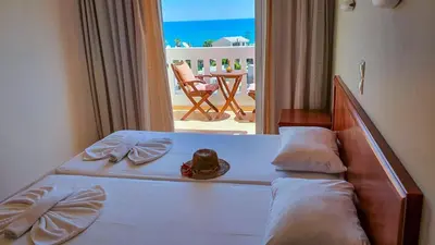 a bedroom with a bed with a view of the ocean at Kalimera Hotel in Agia Marina Nea Kydonias