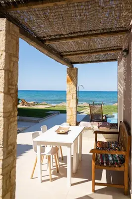 a patio with a table and chairs and the ocean at The Mini Beach Hotel in Stalos