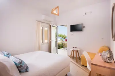 a bedroom with a bed and a television and a table at Hermes Beach Front in Stalos