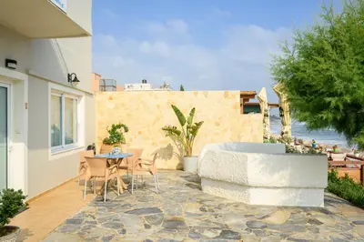 a patio with a table and chairs and the ocean at Hermes Beach Front in Stalos