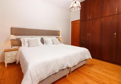 a bedroom with a large white bed and wooden cabinets at Charming and Comfy House in Agia Marina Nea Kydonias