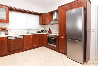 a kitchen with wooden cabinets and a stainless steel refrigerator at Charming and Comfy House in Agia Marina Nea Kydonias