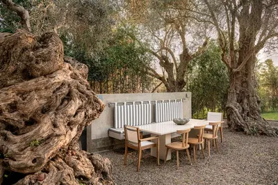 a table and chairs with a bench and trees at Villa 7 in Perivólia