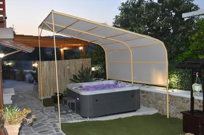 a hot tub under a gazebo in a backyard at George & Helen's House in Ayiá