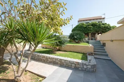 a set of stairs leading to a building with palm trees at Captain's Beach Apartments in Kissamos