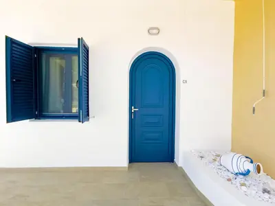 a blue door on the side of a white building at Captain's Beach Apartments in Kissamos