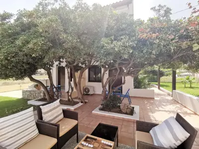 a patio with chairs and tables under a tree at Captain's Beach Apartments in Kissamos
