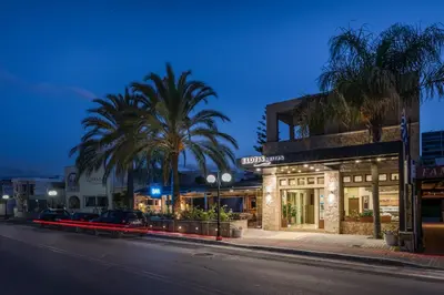 a street with a building and palm trees at night at Elotis Suites in Agia Marina Nea Kydonias