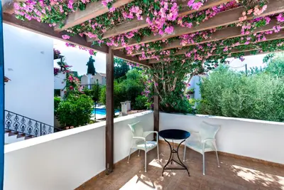 a patio with a pergola with pink flowers at Douliana Villas in Douliana
