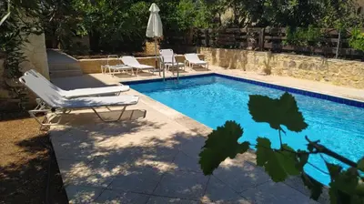 a swimming pool with two lounge chairs and an umbrella at Douliana Villas in Douliana