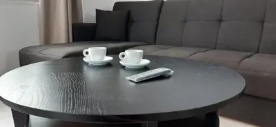 a black coffee table with two cups and a remote control at Thea Apartment in Agia Marina Nea Kydonias