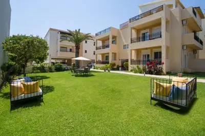 an apartment with a lawn in front of a building at Gianthea Studios and Apt in Stalos