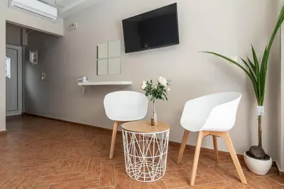 a room with two white chairs and a tv on the wall at Girogiali beach hotel - Adults only in Stalos