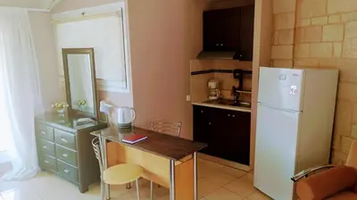 a kitchen with a refrigerator and a table with chairs at Girogiali beach hotel - Adults only in Stalos