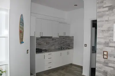 a kitchen with white cabinets and a surfboard on the wall at Bay View Apartments in Plataniás