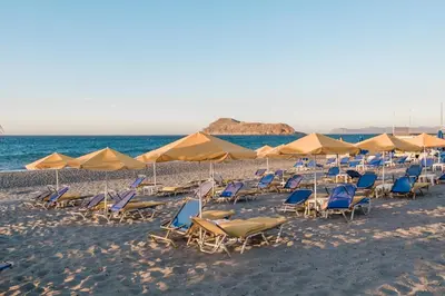 a group of chairs and umbrellas on a beach at Bay View Apartments in Plataniás