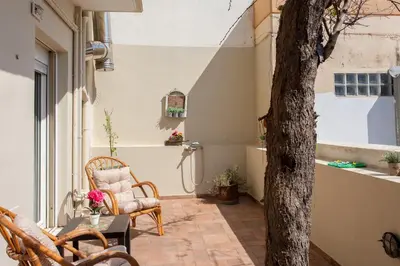 a patio with chairs and a table and a tree at Evelia Apartment in Galatás