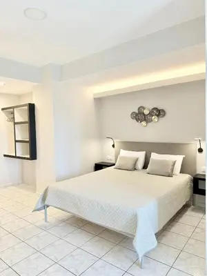 a white bedroom with a large white bed with two pillows at Avenue Hotel Falassarna in Falasarna