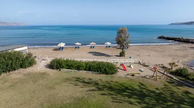 a beach with umbrellas and chairs and the ocean at Ismini Apartments in Kalyves