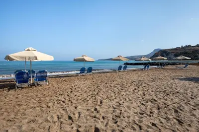 a group of chairs and umbrellas on a beach at Ismini Apartments in Kalyves