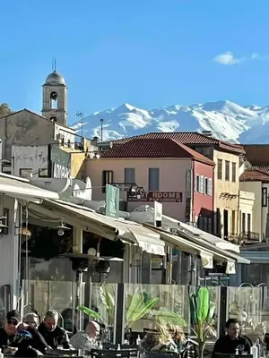 a group of people sitting at a restaurant with mountains in the background at Hotel Lefka Ori - City Rooms in Chania Town
