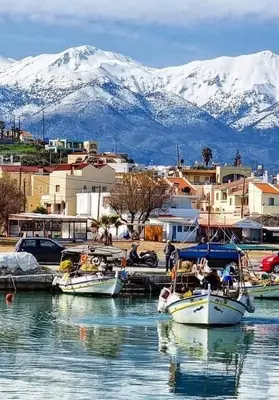 a group of boats docked in a harbor with snow covered mountains at Hotel Lefka Ori - City Rooms in Chania Town