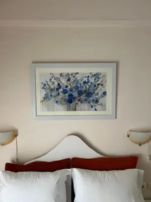 a picture of a vase of blue flowers above a bed at Hotel Lefka Ori - City Rooms in Chania Town