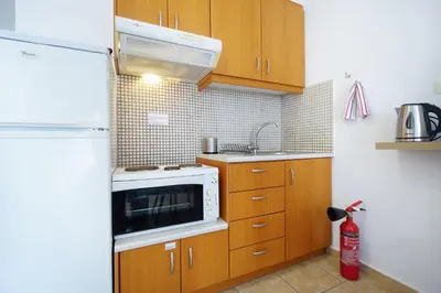 a small kitchen with wooden cabinets and a microwave at Cozy Studio Chania in Chania Town