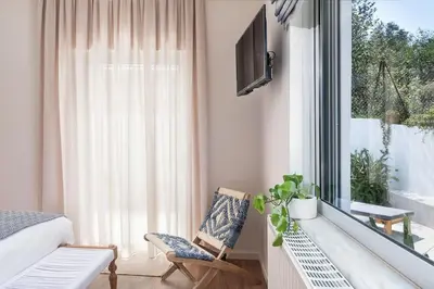 a bedroom with a bed and a window and a chair at Anemone Holiday Apartment in Kato Daratso
