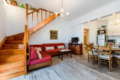 a living room with a red couch and a staircase at Evelinas House Platanias in Plataniás