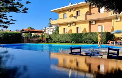 a woman is standing next to a swimming pool in front of a building at Argo Apartments in Kato Daratso