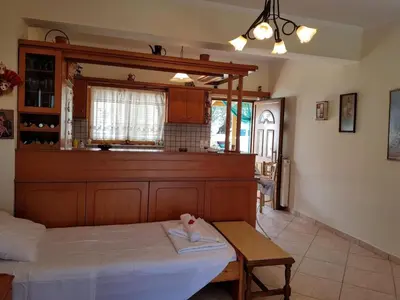 a bedroom with a large bed and a kitchen at Eftihia's Traditional House in Loúlos