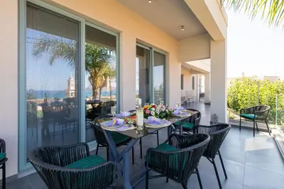 a dining room with a table and chairs on a balcony at Superior Villa Kleanthi in Stalos