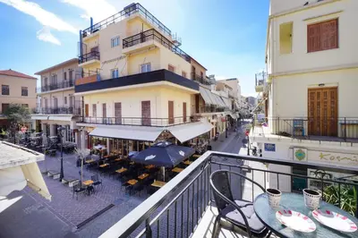 a balcony with tables and umbrellas on a city street at Mare I - studio in Old Harbor in Chania Town