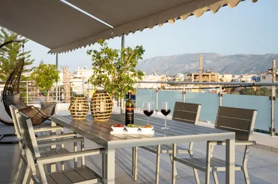 a table and chairs on a balcony with wine glasses at Amaen Apartment in Chania Town