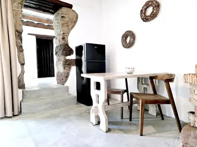 a dining room with a table and a refrigerator at Monastery Estate Guesthouse in Sougia