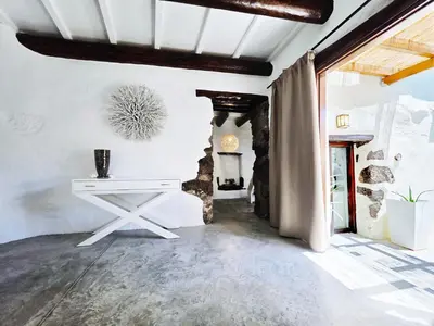 a living room with a white table and a stone wall at Monastery Estate Guesthouse in Sougia