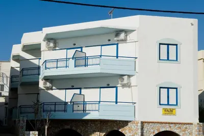 a white building with blue balconies on it at Galini Studios in Palaiochóra