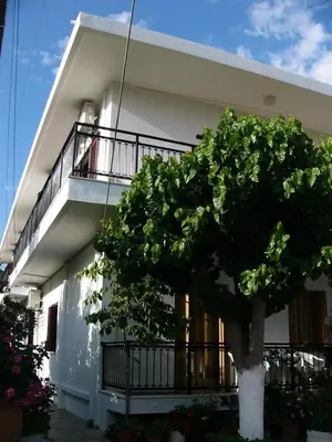 a white building with a tree in front of it at Oasis Studios in Palaiochóra