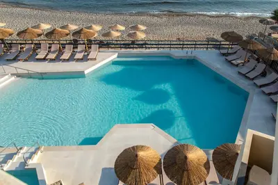 an overhead view of a swimming pool with chairs and umbrellas at Hotel Haris on the beach in Agia Marina Nea Kydonias