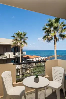 a patio with a table and chairs and the ocean at Hotel Haris on the beach in Agia Marina Nea Kydonias