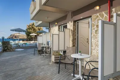 a patio with tables and chairs next to a building at Hotel Haris on the beach in Agia Marina Nea Kydonias