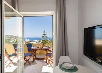 a room with a balcony with a table and a television at Casa di Halepa in Chania Town