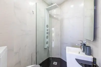 a white bathroom with a shower and a sink at Villa Dione Palace in Falasarna