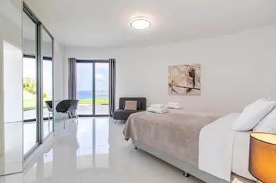 a white bedroom with a bed and a living room at Villa Dione Palace in Falasarna