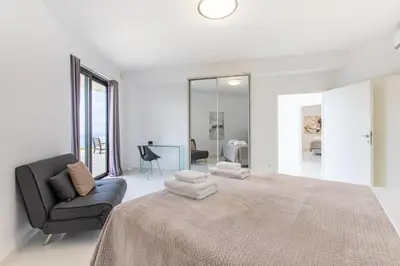 a white bedroom with a large bed and a chair at Villa Dione Palace in Falasarna