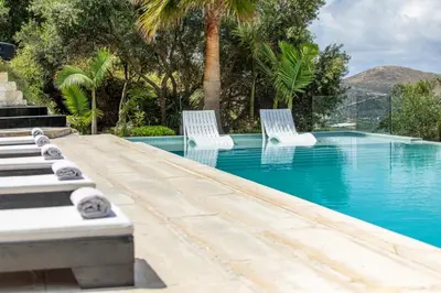 two white chairs sitting next to a swimming pool at Villa Dione Palace in Falasarna