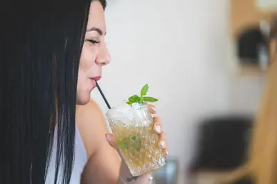 a woman drinking a drink with a straw at Helios Apartments in Kato Daratso