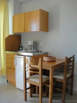 a small kitchen with a table and chairs and a counter at Leonidas Rooms in Plataniás