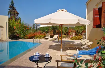 a patio with an umbrella and a pool at Crete holiday rental small village close to beaches -sharing a large pool in Vamos